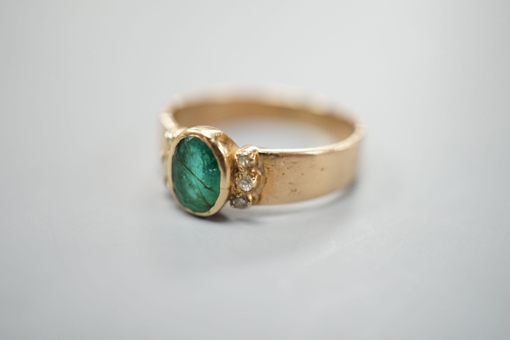 A yellow metal, oval cut emerald and six stone diamond chip set ring, size O, gross weight 3 grams.